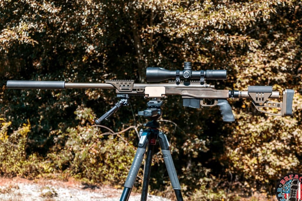 Suppressed rifle mounted to a tripod. 