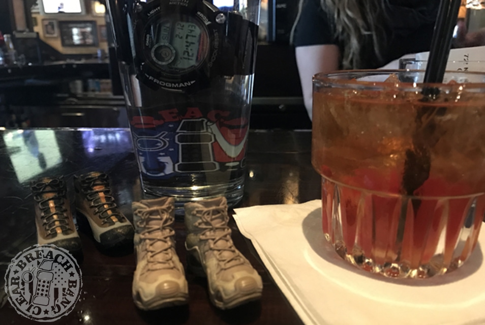 On a bar, the Frogman in a glass with miniature combat boots in front. Drink to the right.