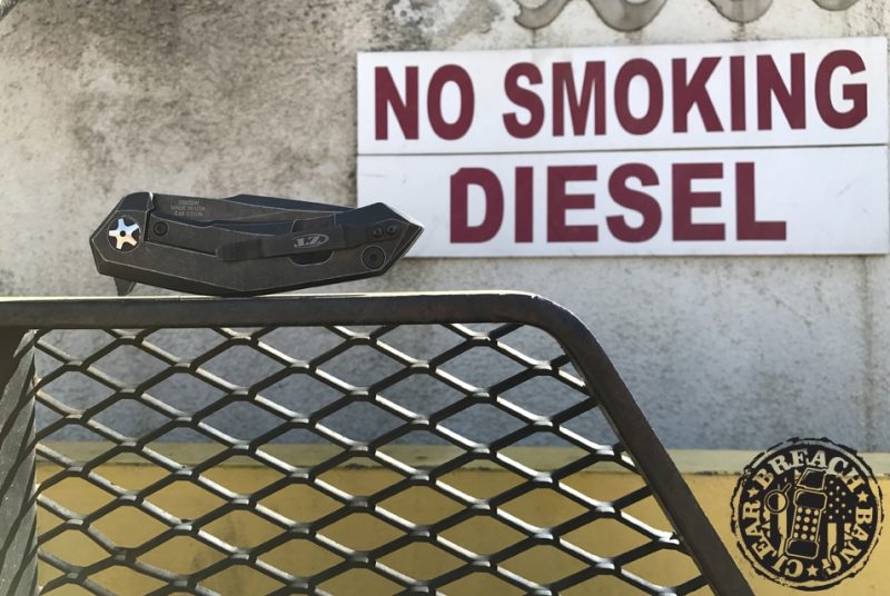Sign in background reads: No smoking. Diesel. Folded knife on a chain fence.
