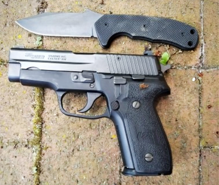 The Emerson Police Utility Knife next to a Sig P228 to illustrate just how compact the PUK is.