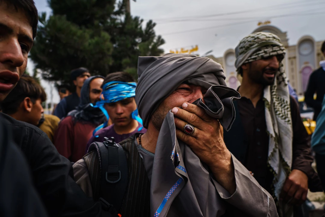 An Afghan man weeps while watching Taliban fighters attack other Afghan civilians in a crowd attempting to reach HKIA. 