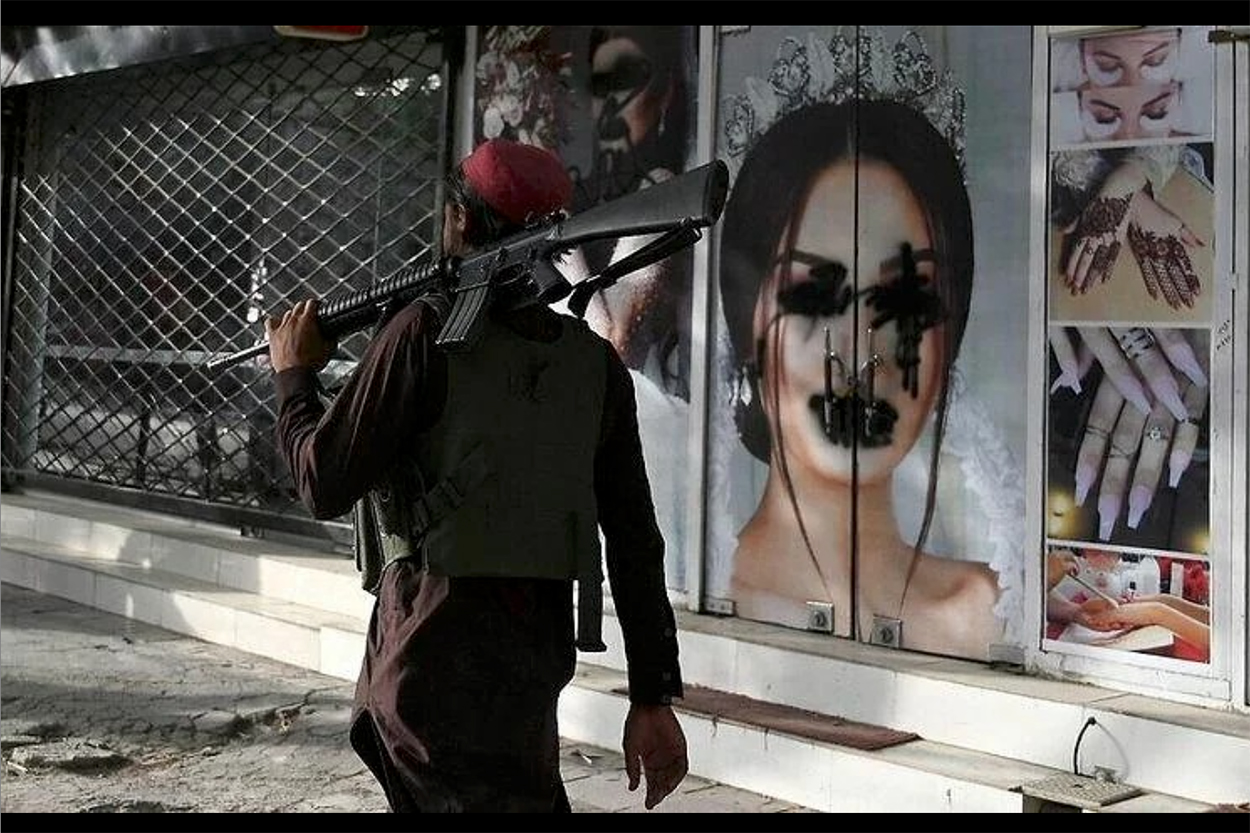 A Taliban fighter walks past the defaced front of a beauty salon in the Shahr-e-Naw of Kabul. 
