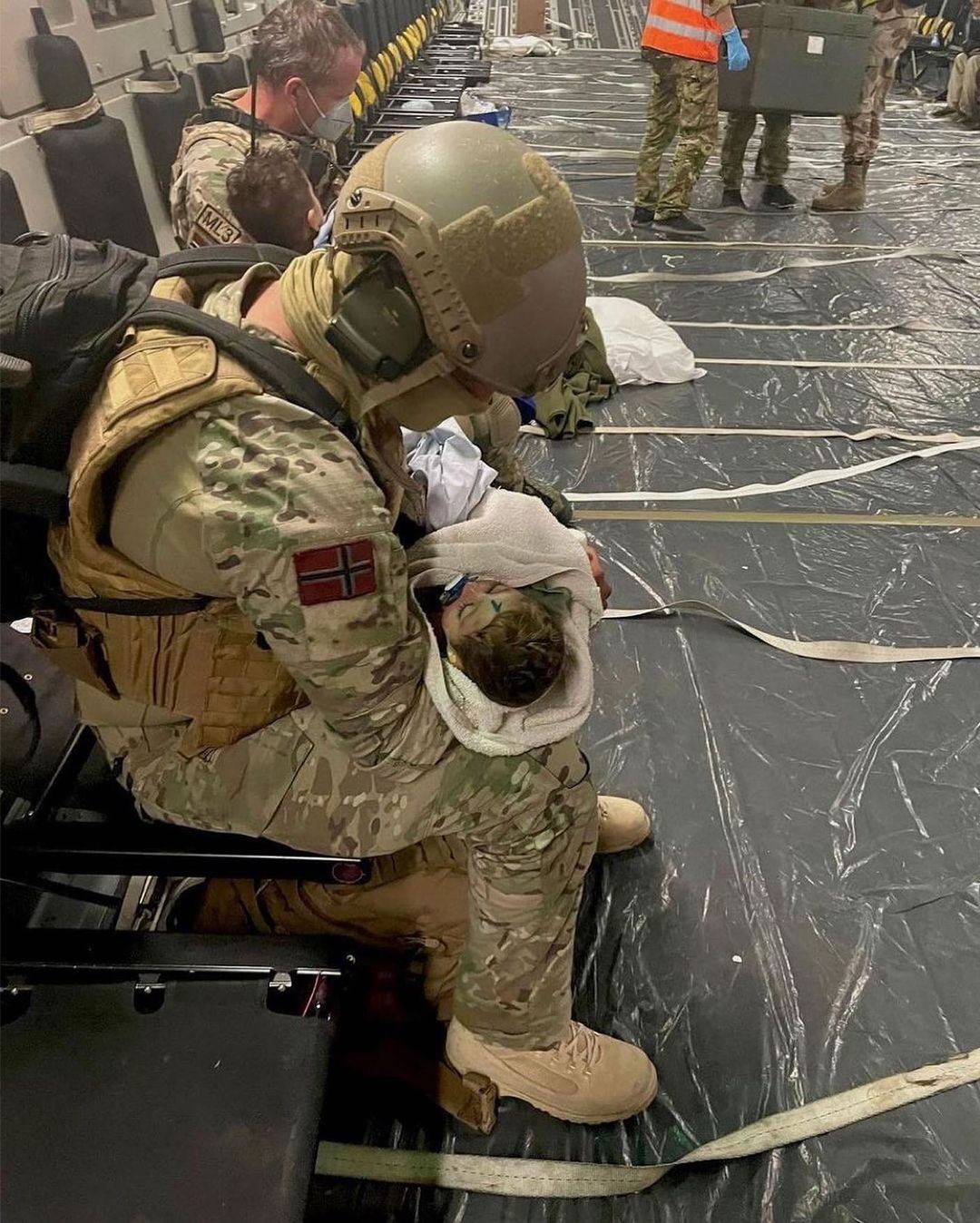 Unidentified Norwegian soldier with unidentified infant on military aircraft scheduled to depart to Oslo from Kabul Intl Airport, several days after Taliban forces took control of Kabul. 