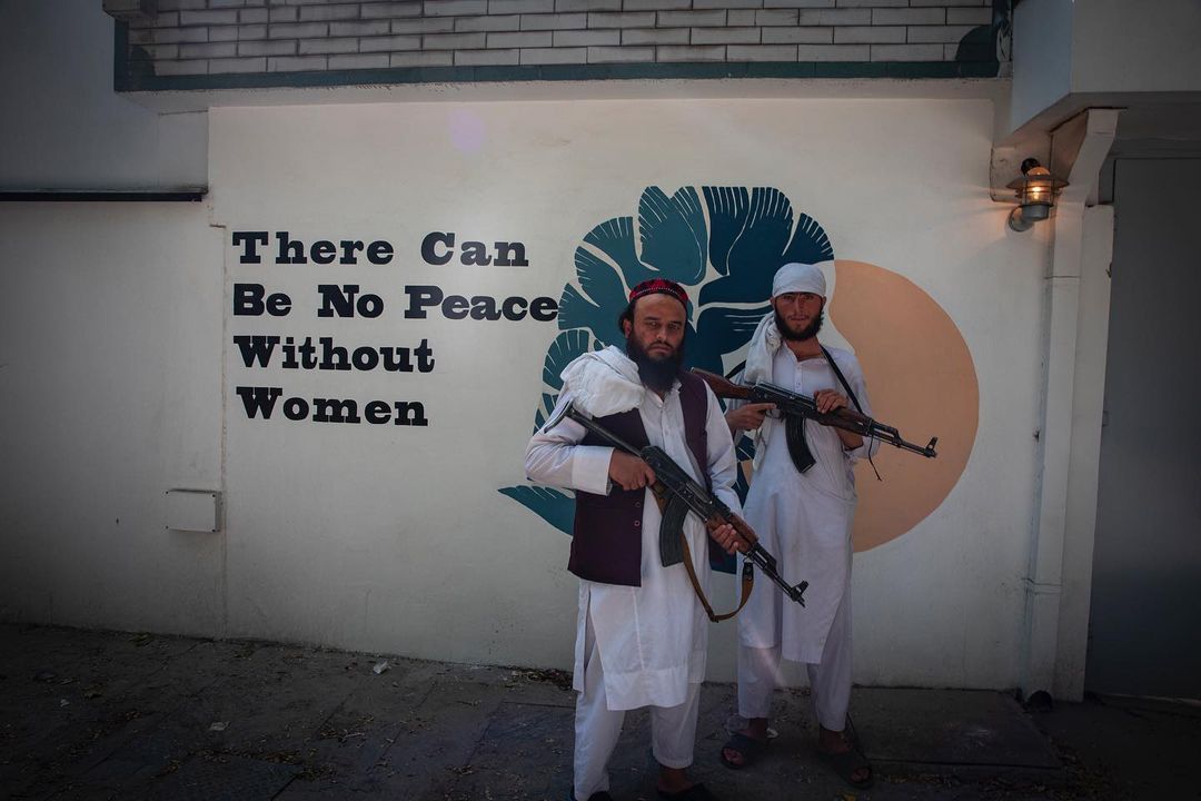 An ironic and unsettling image taken in or near Kabul: Taliban fighters pose near a pro women's rights wall mural. 