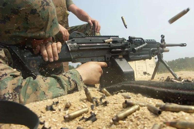 Military soldier firing a belt-fed M249