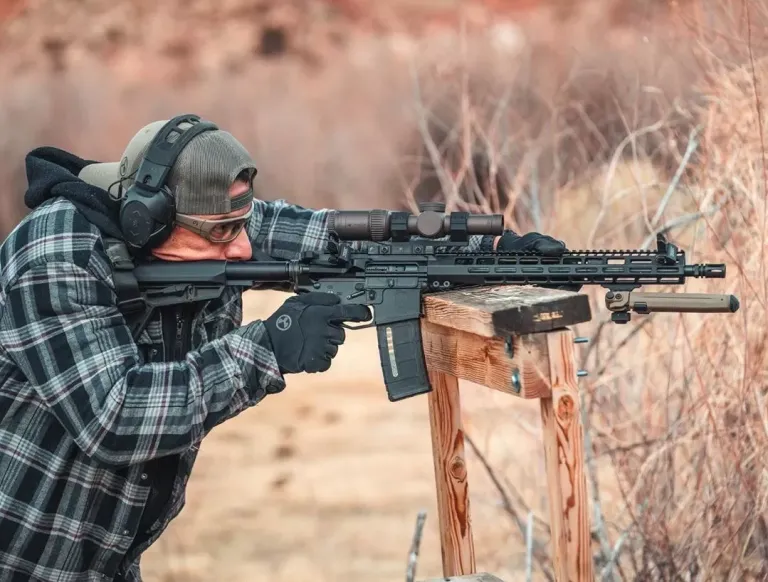 Man in flannel aiming a rifle with proper cheek weld.