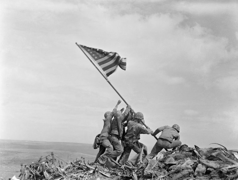 Marines and a Corpsman raising the U.S. flag atop Mt. Suribachi on Iwo Jima.